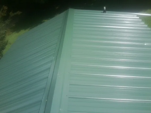 New green metal panels meeting at the ridge of a roof — Flat Roof Repair work by our crew in Markle