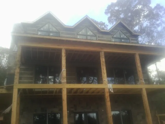 Dormers and porch framing on a large log home under construction — Roof Coating work by our crew in Markle
