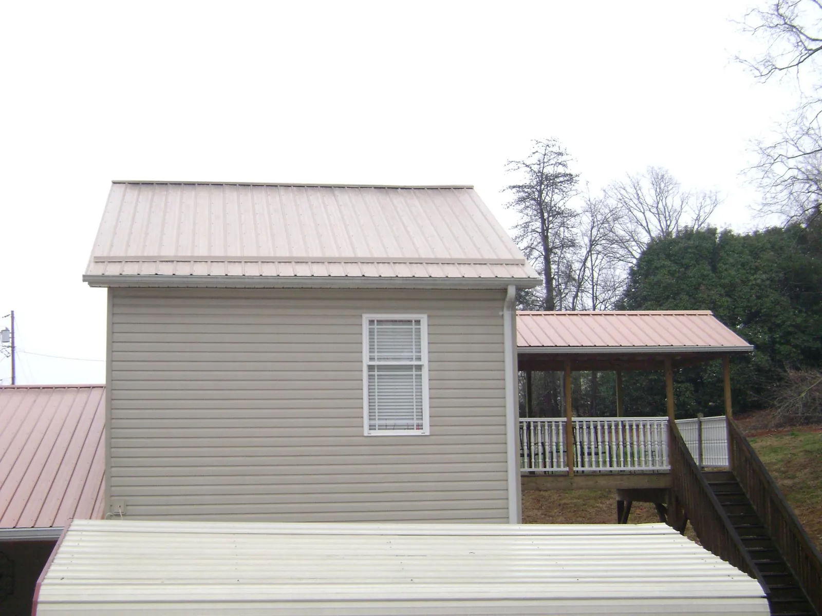 Tan metal roofs on a two story addition and attached porch, from a Roof Replacement job in Markle