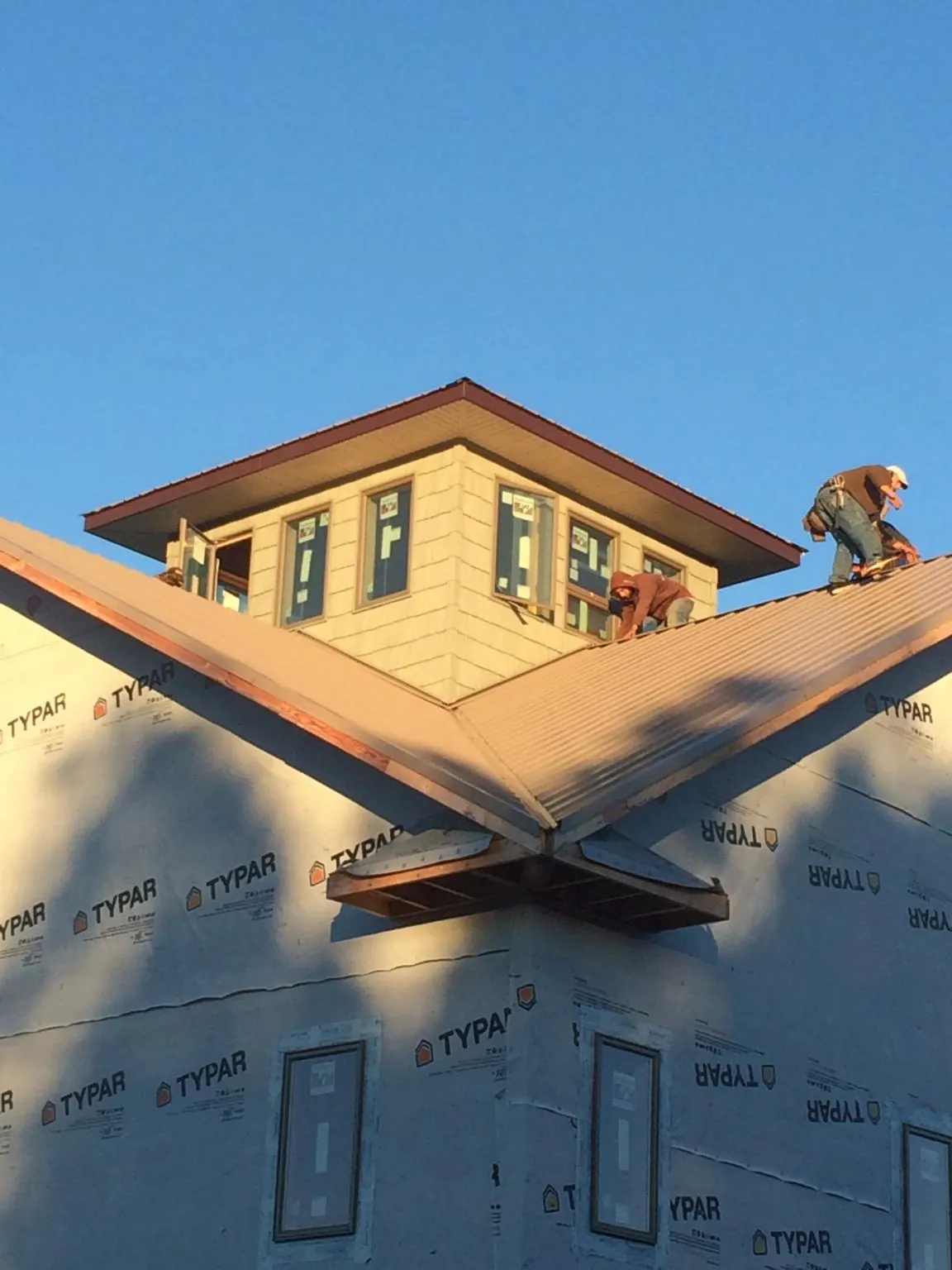 Roofers working around a rooftop cupola on a new metal roof at sunset — Roof Waterproofing in Markle by Roofing Brothers